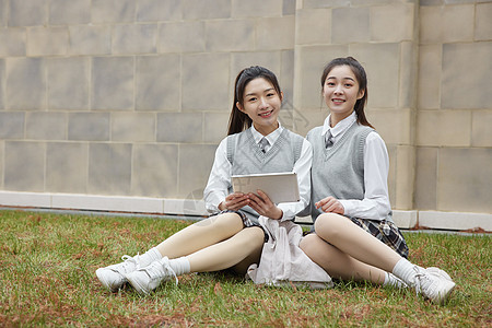 美女学同学拿平板电脑坐在草地上图片