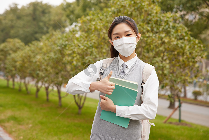 戴口罩的美女学生抱着书本点赞形象图片