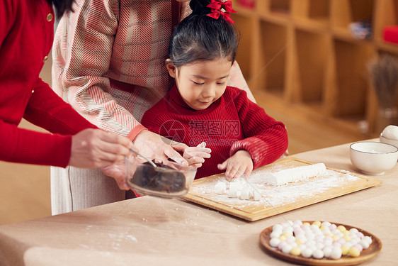 奶奶和妈妈指导小女孩包汤圆图片