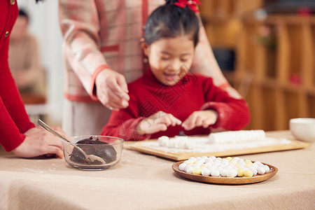 奶奶和妈妈指导小女孩包汤圆图片