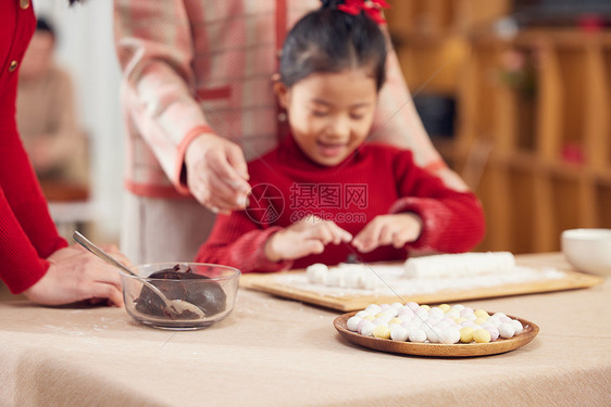 奶奶和妈妈指导小女孩包汤圆图片