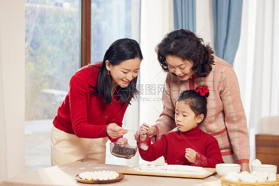 奶奶和妈妈指导小女孩包汤圆图片