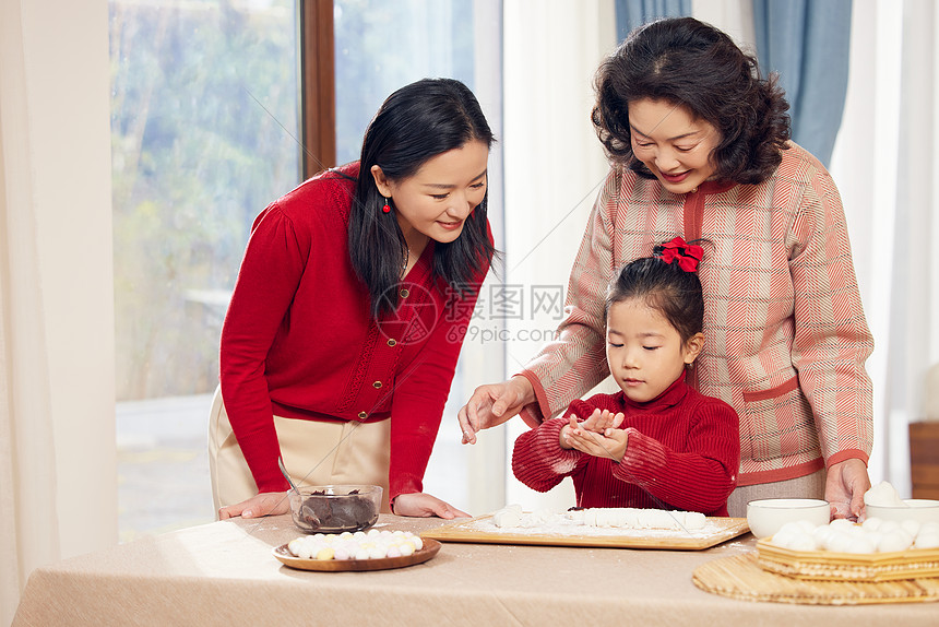 奶奶和妈妈指导小女孩包汤圆图片