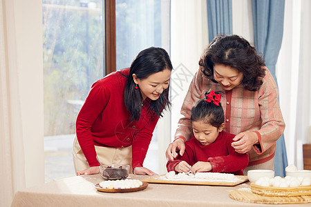 奶奶和妈妈指导小女孩包汤圆图片