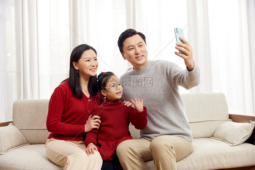春节一家三口拿着手机自拍图片