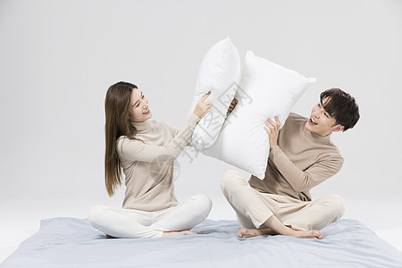 韩系情侣用枕头嬉戏打闹图片