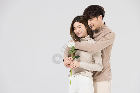 韩系情侣亲密拥抱手拿玫瑰花背景图片