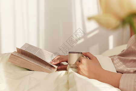 女性卧床看书喝咖啡图片