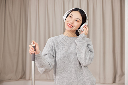 青年女性做清洁戴耳机听音乐背景图片