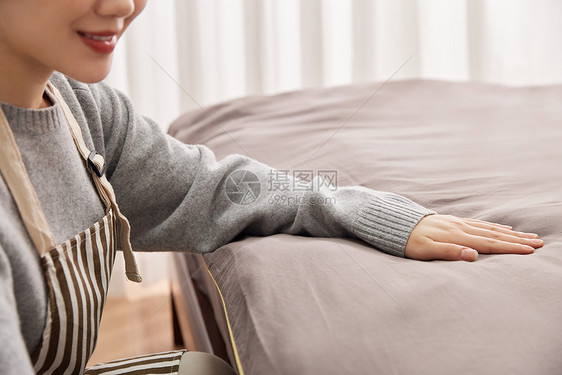 青年女性居家整理床铺特写图片