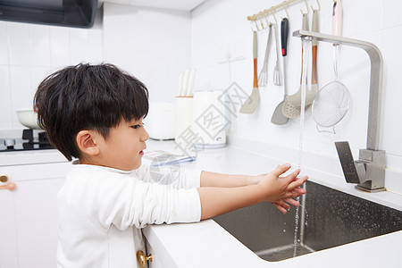 在厨房水池洗手的小男孩图片