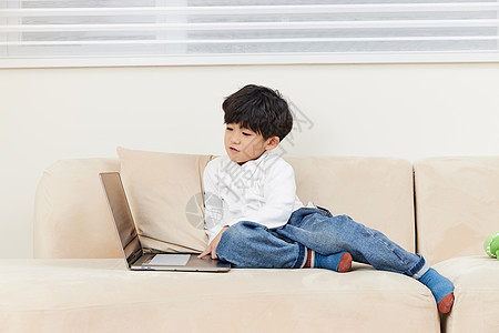 坐在沙发上看电脑的小男孩图片