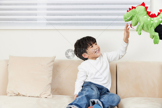 小男孩在沙发上跟玩偶玩耍图片