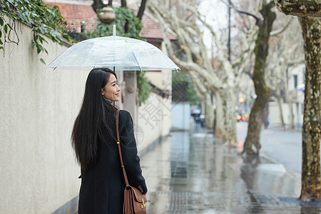 下雨天撑伞走在路边的女性图片