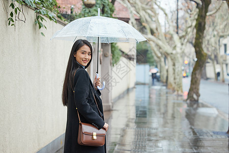 下雨天与雨伞打着雨伞的女性回头背景