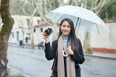 下雨天撑着伞的女摄影师背景图片