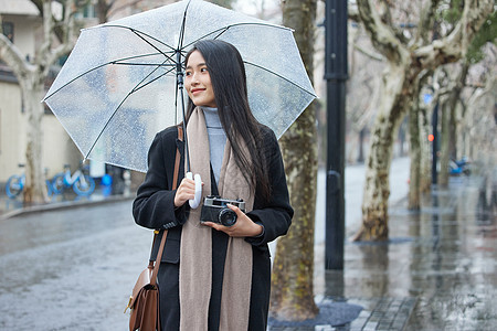 下雨天撑着伞的女摄影师图片