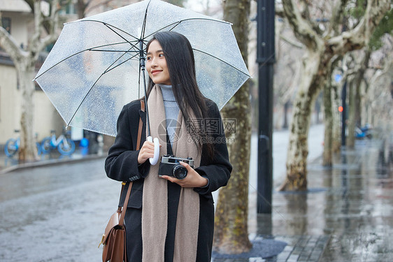 下雨天撑着伞的女摄影师图片