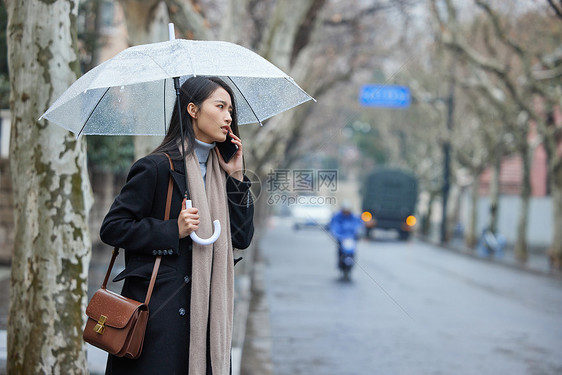 路边撑着雨伞着急打电话的女性图片