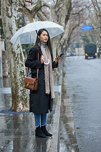 下雨天在路边着急等车的女性背景图片