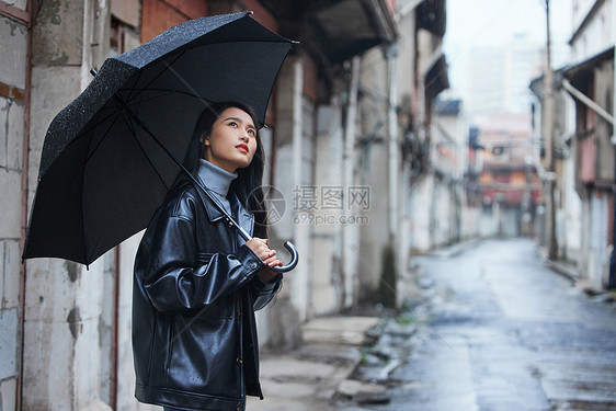 屋檐下等雨停的女性图片