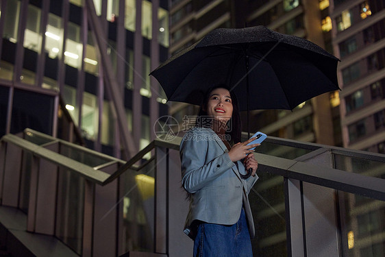 雨天城市夜晚使用手机的商务女性图片