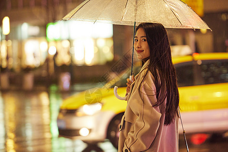 下雨夜晚撑伞走路的女性图片