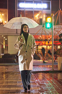 下雨夜晚过马路的都市女性图片