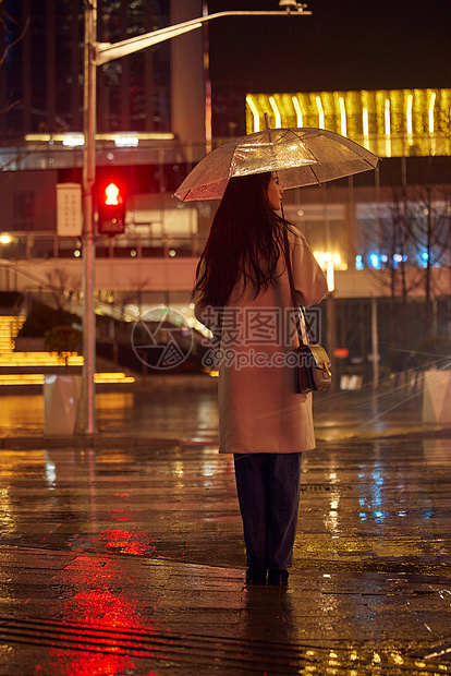 下雨天撑伞等红绿灯的女性背影图片