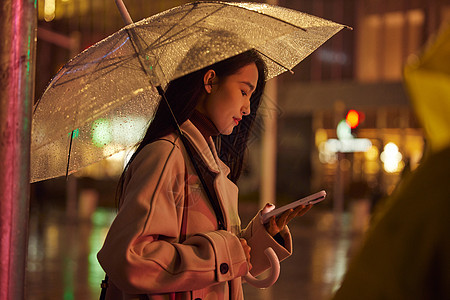 下雨天站在路边看手机的都市女性图片