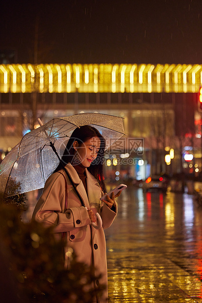 下雨天站在路边看手机的女性图片