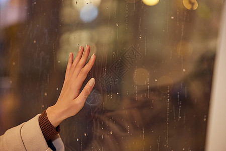 下雨天窗前女性手部特写图片