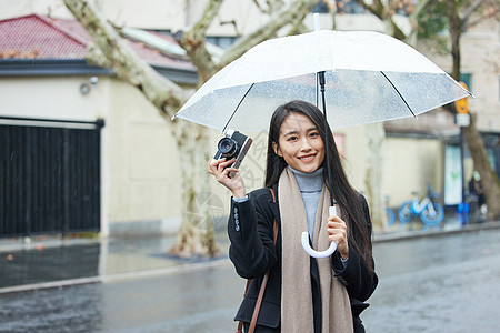 下雨天撑着伞的女性手拿照相机背景图片