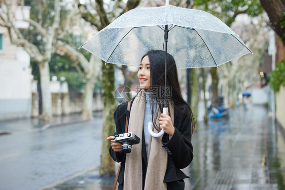 下雨天撑着伞的女性手拿照相机图片