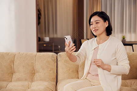 中年短发女性在家用手机视频通话背景图片
