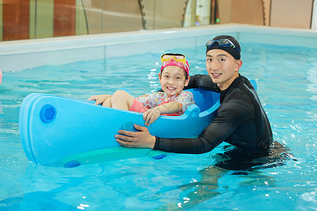 游泳教练带小女孩体验水上设施图片