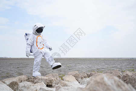 穿着宇航服的男性海边行走探索图片