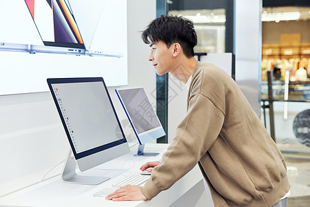 数码店选购电脑的年轻男性背景图片