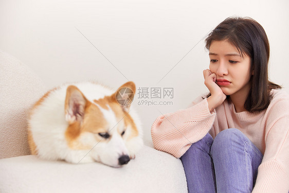 看着宠物犬表情不开心的女性图片