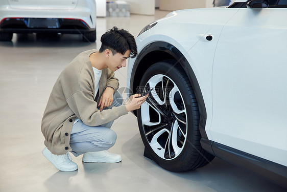 汽车4s店查看轮胎的青年男性图片