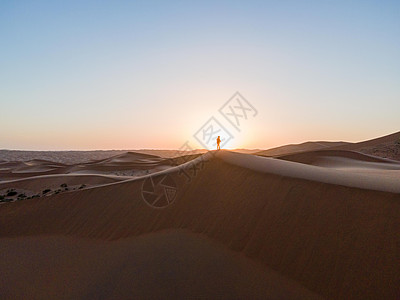 沙漠中徒步的人站在夕阳下高清图片
