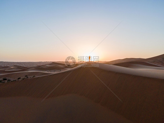 沙漠中徒步的人站在夕阳下图片