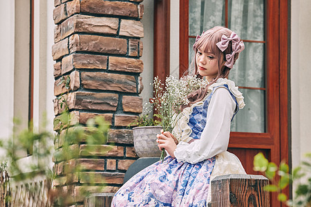 漫画愿景手捧鲜花坐在窗前的洛丽塔女孩背景