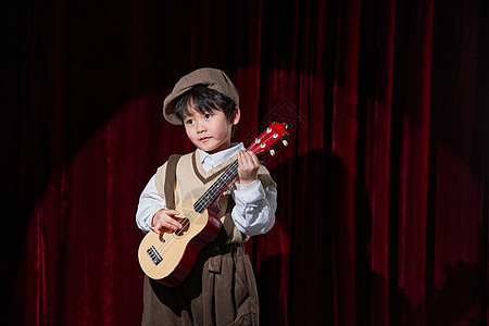 舞台上表演尤克里里的小男孩背景图片