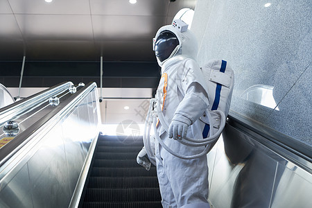穿宇航员的男性乘坐地铁电梯高清图片