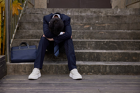 中年男性坐在台阶上低头苦恼图片素材