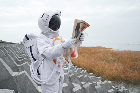 穿着宇航服的男性看报纸背景图片