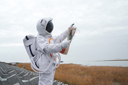 穿着宇航服看报纸的男性背景图片