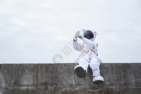 穿着宇航服的男性坐在海边自拍图片