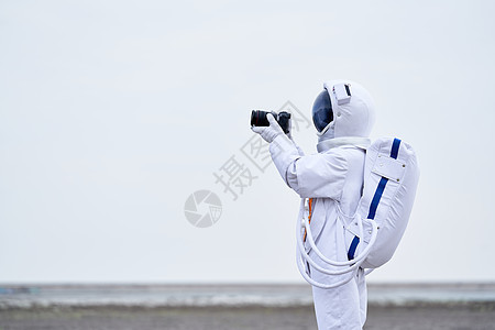 穿着宇航服的男性拿单反拍摄背景图片